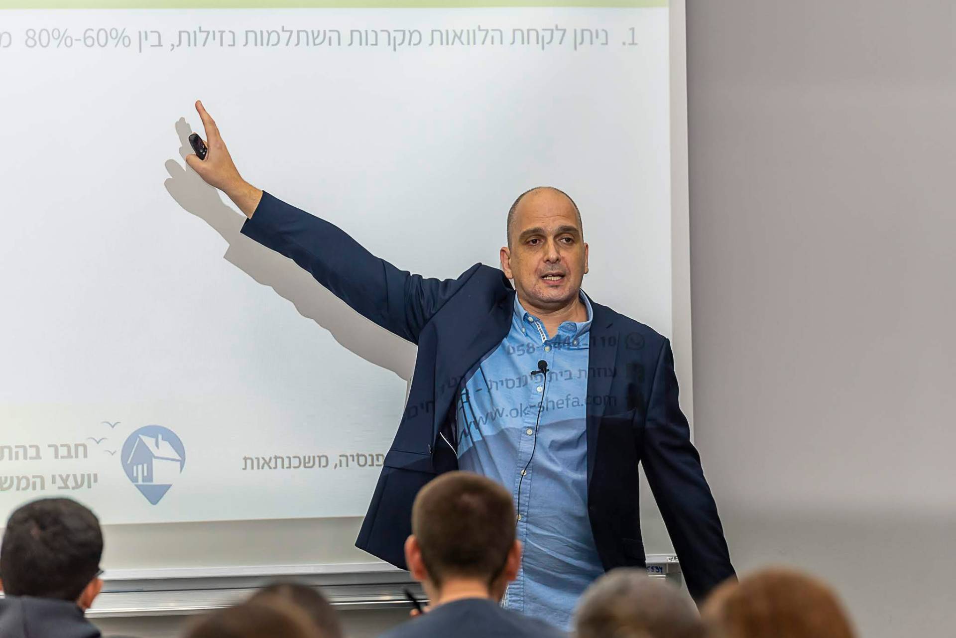 אורן קכל מרצה בפני קהל על השקעות נדל״ן ומשכנתאות